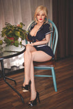 Jenny sitting in a blue and brown wood chair with her legs crossed, wearing a sexy sailor outfit with mini-skirt and matching top.