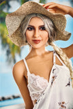 Stunning Kaja holds her hat down on a breezy beech, wearing a white bra and white beach dress.