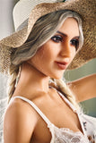 A closeup from the side of Kaja's beautiful face, with her plantinum blonde braids issuing from her wide-brimmed, rolled-up straw hat.