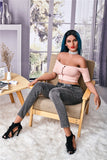 Full body shot of 5ft 7in Aliciana, seated in a occasional-style armchair, wearing grey denim pants and a low cut pink high fashion crop top.